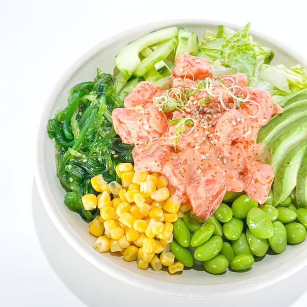 Pokérrito Ya poke bowl with salmon, seaweed, corn, edamame, avocado, cucumber, and lettuce.