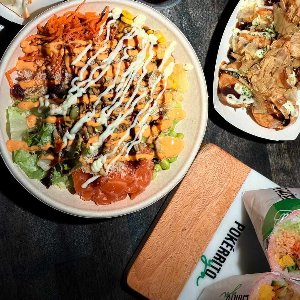 A Pokérrito Ya poke bowl with salmon, vegetables, and sauces, next to takoyaki and poke burritos.